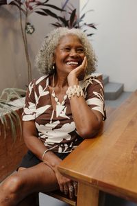 Happy senior woman sitting indoors, exuding warmth and joy in a modern setting.